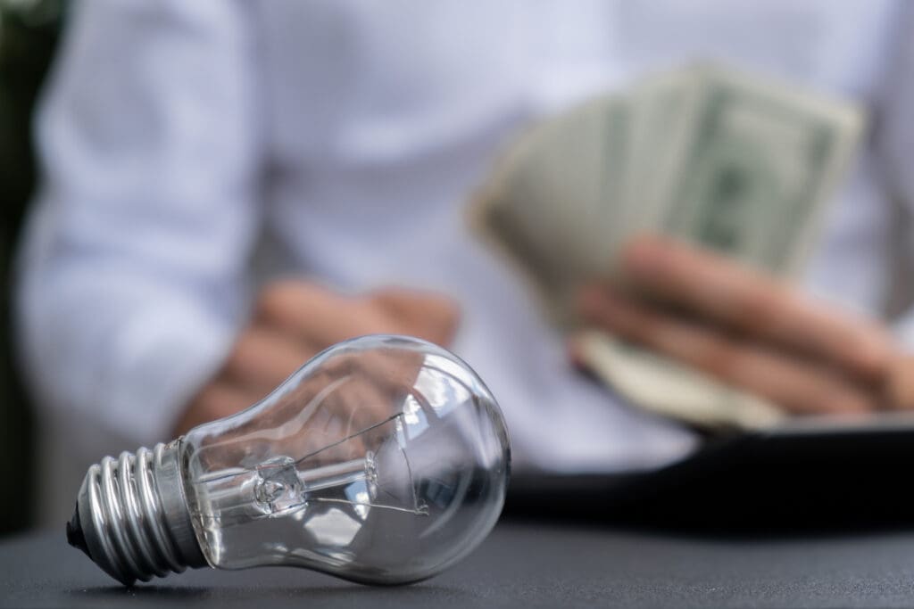 lightbulb with person holding rebate money behind it